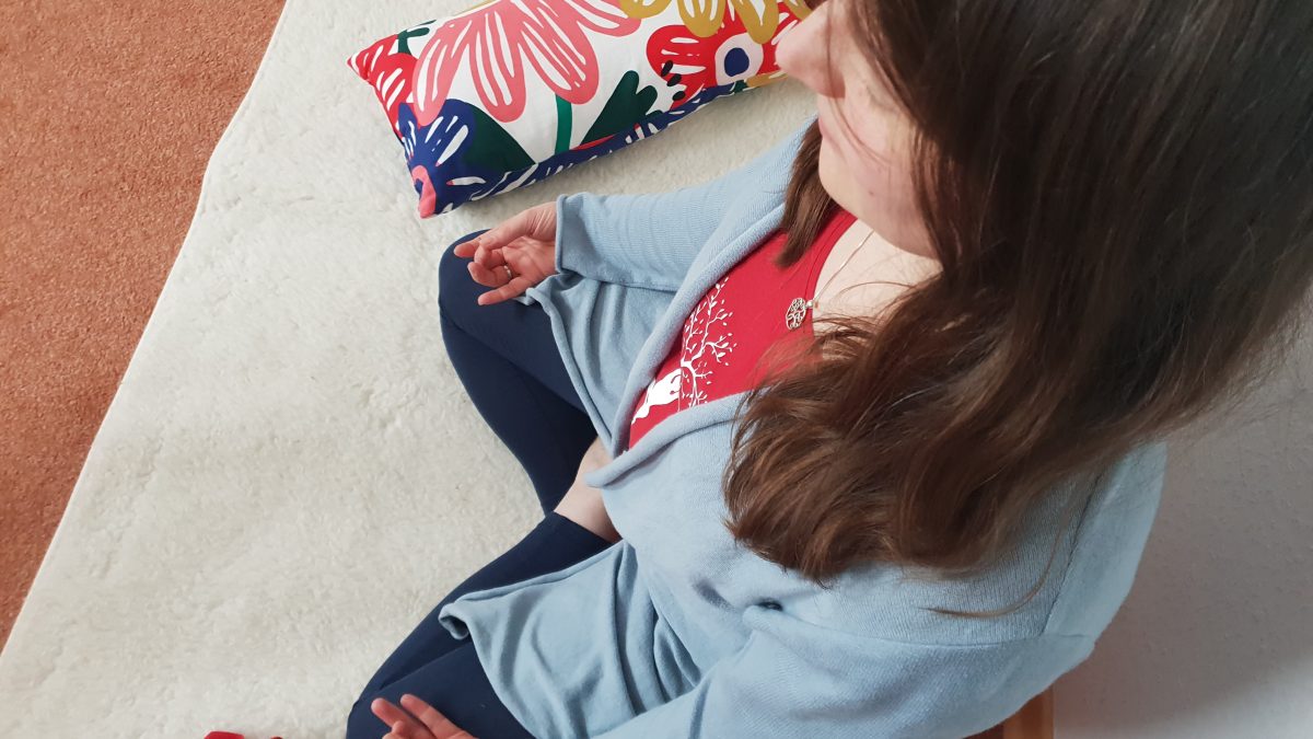 Marion meditiert auf ihrer Yogamatte mit geschlossenen Augen