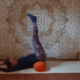 Marion übt Yin Yoga und die Position Seegras. Sie liegt auf dem Rücken, die Arme über dem Kopf abgelegt. Die Beine sind locker zur Decke gestreckt, das Becken liegt erhöht auf einer Yogarolle.